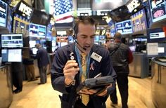 a man wearing headphones is looking at his cell phone in the middle of a trading floor