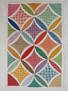 a multicolored quilt is displayed on a white surface and it looks like an abstract design