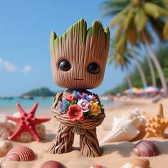 a baby groote is standing on the beach with shells and flowers in his hands