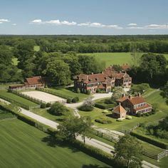 an aerial view of a large house surrounded by lush green fields and trees in the distance