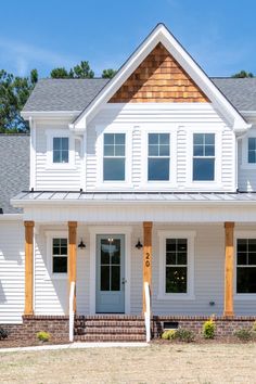 a large white house with two story windows and wood trimming on the front porch