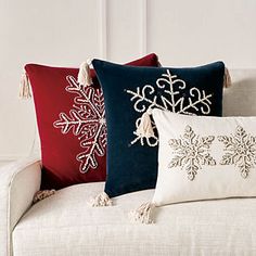 four pillows on a couch with tassels and snowflakes in red, white and blue