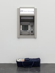 an atm machine sitting on top of a floor next to a blue duffel bag