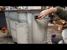 a man is painting an old dresser with white paint