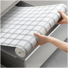 a person is holding a roll of paper in front of a file cabinet with drawers