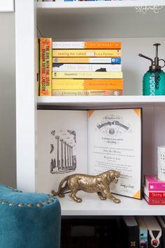 a bookshelf filled with lots of books next to a blue chair and lamp