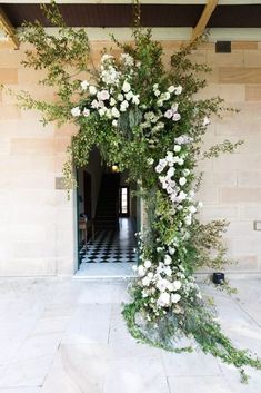 a white flowered arch in front of a building with black and white checkered flooring