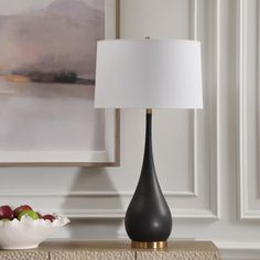 a table lamp sitting on top of a dresser next to a bowl of fruit