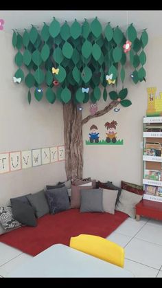 a room with a couch, tree and bookshelves on the wall in front of it