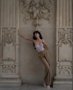 a woman leaning against a wall with her hand on the back of her head and arms stretched out