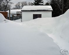 the snow is piled up on top of the house and in front of the building