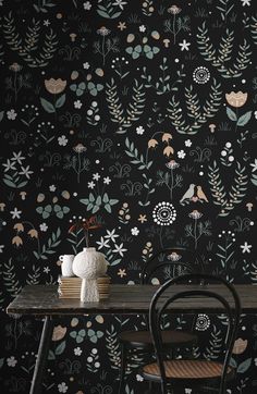 a table with two chairs and a vase on it in front of a floral wallpaper