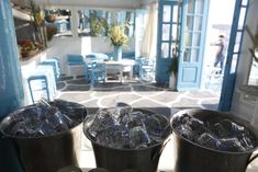 two buckets filled with ice sitting on top of a counter next to blue chairs