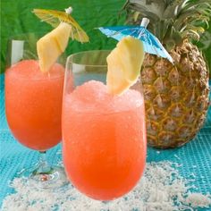 two glasses filled with drinks sitting on top of a blue table cloth next to a pineapple