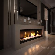 a modern fireplace is lit in the middle of a room with candles on either side