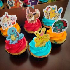 cupcakes with pokemon characters on them sitting on a table in front of other cupcakes