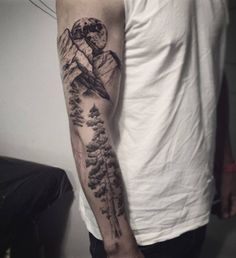 a man with a mountain and trees tattoo on his arm