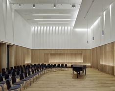 an empty room with rows of chairs and a piano in front of a wall full of wooden slats