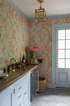 a kitchen with floral wallpaper and white cabinets