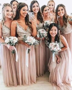 a group of women standing next to each other wearing dresses and holding bouquets in their hands