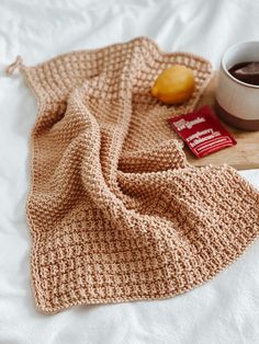 a cup of coffee and a crocheted blanket on a bed