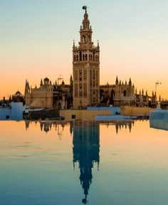 a large building with a clock tower in the middle of it's reflection pool