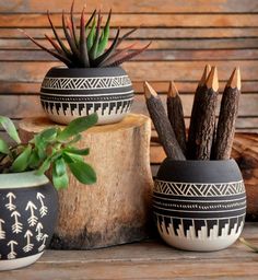 two black and white planters sitting next to each other on top of a tree stump