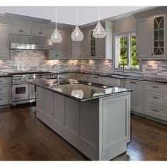 a large kitchen with an island in the middle and lots of lights hanging from the ceiling