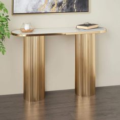 a gold console table with two books on it and a plant in the corner next to it