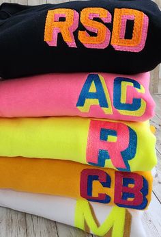 Neon color block shadow font sweatshirts.  Here's how to order: 1) Initials NO MORE than 3 letters 2) Thread color for top color 3) Thread color for the shadow ** If you do not select a color, the colors on the examples will be selected.  (The Sappire sweatshirt with neon yellow and neon pink thread). Sporty Crew Neck Sweatshirt With Color Matching, Yellow Color Block Crew Neck Sweatshirt, Sporty Multicolor Letter Print Sweatshirt, Neon Sweatshirt, Shadow Font, Applique Sweatshirt, Block Fonts, Block Font, Pink Thread