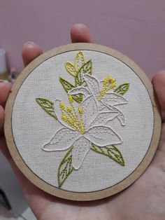 a person holding up a small embroidered flower