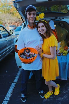 a man and woman standing next to each other in front of a car