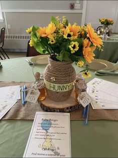 a table topped with a vase filled with yellow flowers next to a menu and place cards