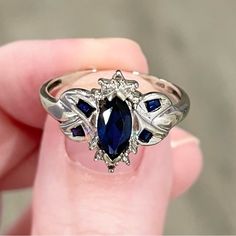 Lovely Statement Ring! Featuring A 8x4mm Marquis Lab Created Medium/Dark Blue Sapphire, And Four Lab Created Sapphire Baguette Accents, And Two Diamond Chips; Set In 10k Solid White Gold. Marked 10k And Acid Tested. This Ring Is Between A Size 7.25 And 7.5 This Ring Weighs 2.20g This Ring Measures 13mm From The Front; And 1.5mm From The Back Of The Band. Vintage Condition: Fair (Heavy Scratches On The Back Of The Band; Some Minor Wear On The Marquis Stone; The Band Is Slightly Out Of Round). Sapphire Halo Ring, Sapphire Wedding Ring, Sapphire Wedding Rings, White Gold Ring, Sapphire Diamond, Womens Jewelry Rings, White Gold Rings, Statement Ring, Blue And Silver