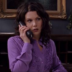 a woman sitting at a table talking on a cell phone