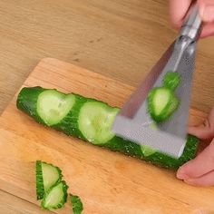 a person cutting cucumbers with a knife on top of a cutting board,