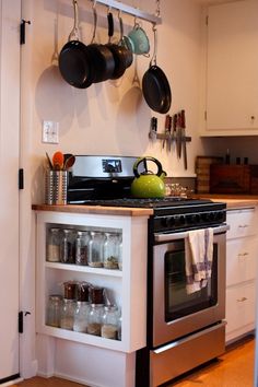 a kitchen with pots and pans hanging on the wall next to an open oven