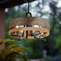 a wooden chandelier hanging from a ceiling in a room with potted plants