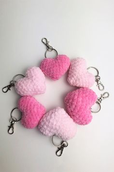 pink and white crocheted heart keychains with metal hooks on a white background