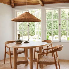 a dining room table with chairs and a basket hanging from it's center point