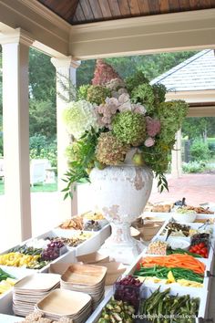 an outdoor summer party with lots of food on the table and flowers in a vase