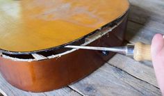 a guitar being worked on by someone using a brush to paint the back of it