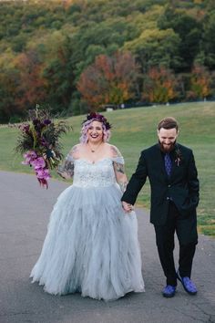 a bride and groom walking down the road holding hands