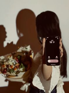 a woman holding up her cell phone to take a selfie in front of a plate of food