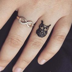 a woman's hand with an owl tattoo on the ring and diamond wedding band