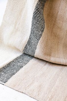 a black and white striped tie laying on top of a beige pillow cover next to a wall