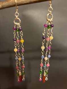 Artisan designed and handcrafted one of a kind, these clusters earrings features, wire wrapped, multi-colors purple lavender amethyst, rose chalcedony, pink amethyst, purple chalcedony, green peridot crystal quartz, and blue agate, dangle gemstone's colors, clusters are mounted on Sterling silver pins with tiny beads for extra attractiveness. Faceted and wire wrapped pink tourmaline teardrop briolette dangle along with clusters of long colorful gemstones. These chains of rainbow colors, sparkling gemstones are connected to the ring above them and the ring under the lever back earring wire. So pretty, they have beautiful movement!  These earrings are fun and will make a lovely gift.  Total measurement length 5 inches long including the lever back earring wire, width 3/4 inches, drop length Colorful Gemstones, Purple Chalcedony, Lavender Amethyst, Peridot Crystal, Earring Wire, Tiny Beads, Earring Ideas, Colors Purple, Purple Lavender