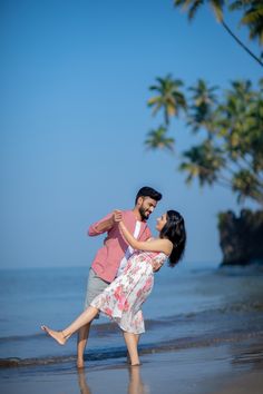 a man and woman dancing on the beach with palm trees in the backgroud