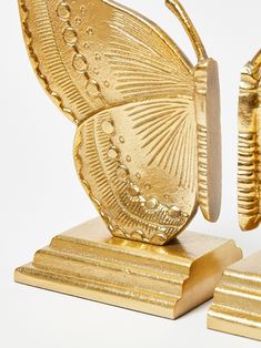 a gold butterfly figurine sitting on top of two pieces of brass foil next to each other