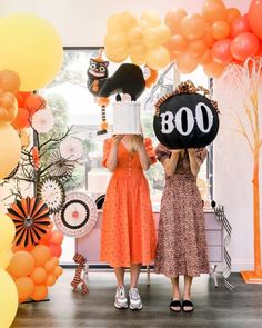 two women standing in front of an entrance with balloons